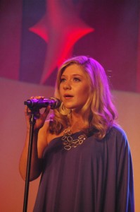 A woman in a blue dress singing into a microphone.