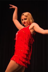 A woman in a red dress dancing on stage.