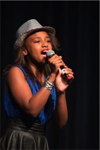 A young woman singing into a microphone.