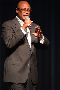 A man in a suit speaking into a microphone.