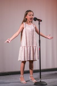 A young girl singing into a microphone.