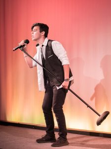 A young man holding a microphone on stage.