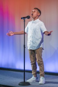 A young boy is singing into a microphone.