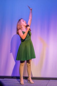 A woman in a green dress singing into a microphone.