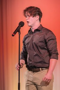 A young man singing into a microphone.