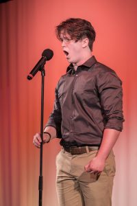 A young man singing into a microphone.