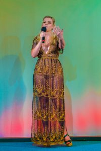 A woman in a gold dress is holding a microphone.