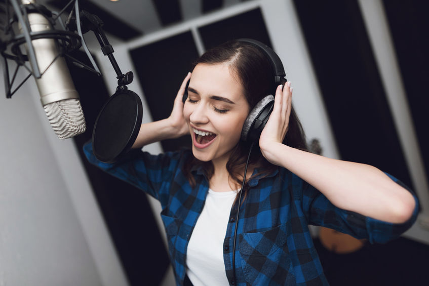 A woman singing a song in a modern recording studio