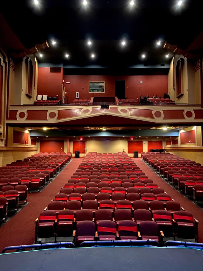 An auditorium with rows of red seats.