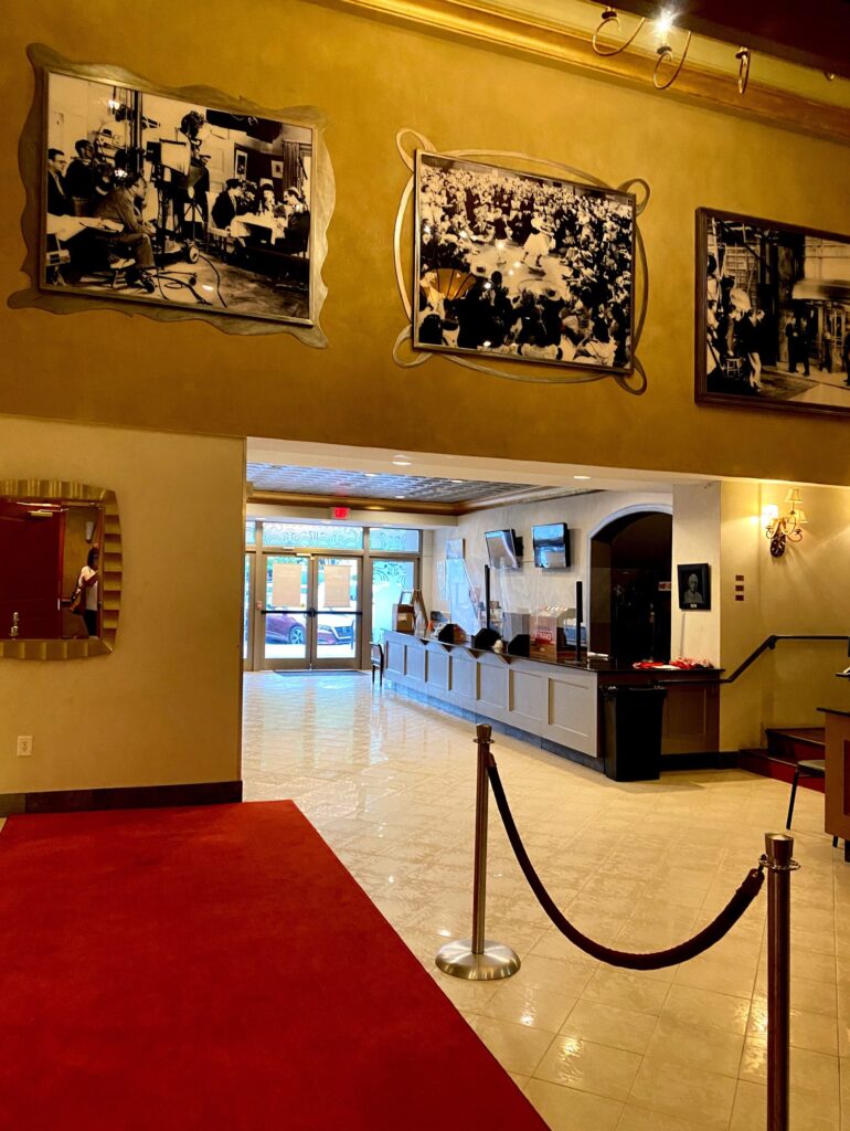 A lobby with a red carpet and pictures on the wall.