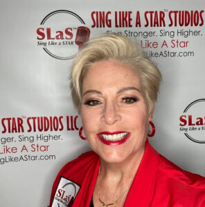 A woman in red standing in front of a sign for sing like a star studios.