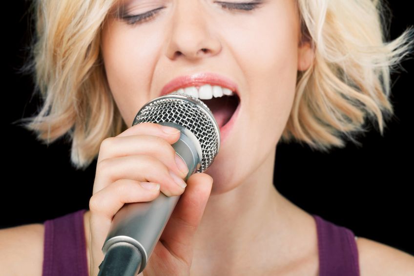 Woman singing into a microphone.